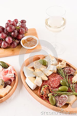 Vertical composition with antipasti plate - variety of cheeses, sausages served with glass of wine, sun dried tomatoes, olives Stock Photo