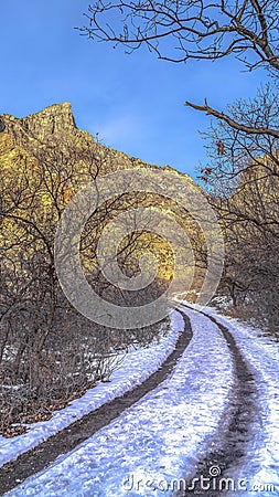 Vertical crop Dirt road trail with tire track and snow in winter in Provo Canyon mountain Stock Photo
