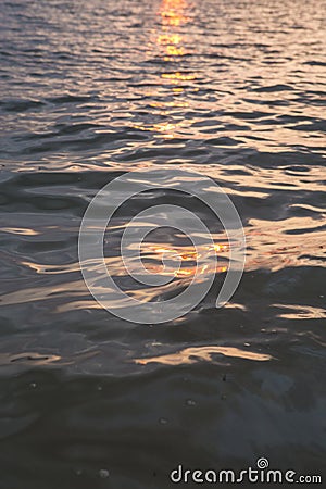 Vertical filled frame full screen desktop wallpaper shot of evening calm sea at dusk with orange sun reflection that makes the Stock Photo