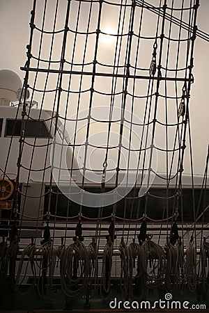 A vertical filled frame wallpaper photo of a net on a mast of a tall ship with plaited ropes and forming unordinary lines and Stock Photo