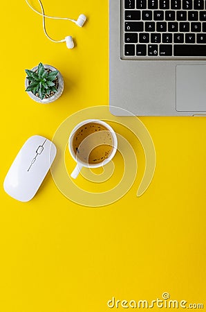 Vertical flat lay minimal home office yellow workspace. Silver laptop and cup of tea. Top view work at home concept Stock Photo