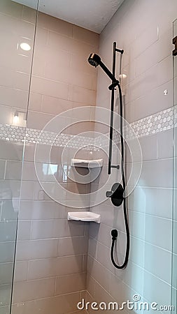 Vertical frame Black round shower head on tile wall of shower stall with hinged glass door Stock Photo