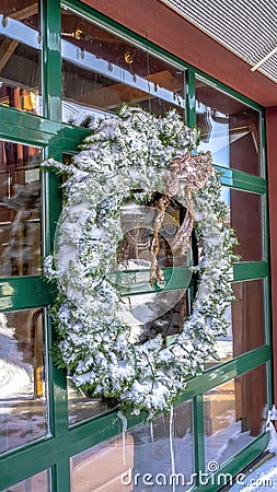 Vertical frame Frosted wreath on the glass wall of building that reflects the winter landscape Stock Photo