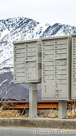 Vertical frame Mailboxes with compartments and numbers against snowy mountain and cloudy sky Stock Photo