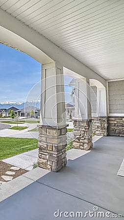 Vertical frame Porch with pillars and a combination of concrete and stone brick exterior walls Stock Photo