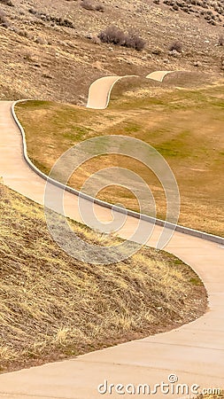 Vertical frame Winding narrow rural road through foothills Stock Photo