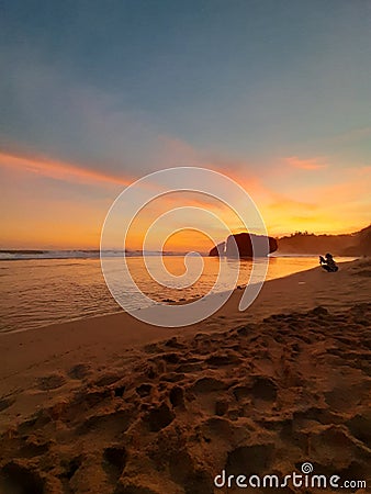 Vertical full length view through the sandy beach with golden sea water at sunset Stock Photo