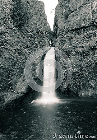 Vertical grayscale shot of a strong waterfall flowing in the river Stock Photo