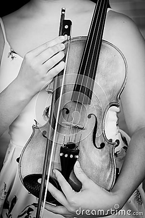 Vertical greyscale shot of a female holding a violin in her arms Stock Photo