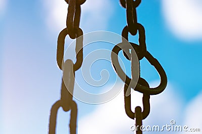 Vertical hanging rusty chain. Sunlight, blue background. For text area Stock Photo