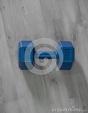 Vertical high angle shot of a 4KG blue dumbbell on the wooden floor Stock Photo