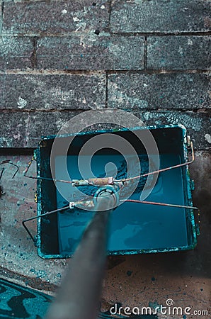 Vertical high angle shot of a mop put in a bucket of blue paint on a stone surface Stock Photo