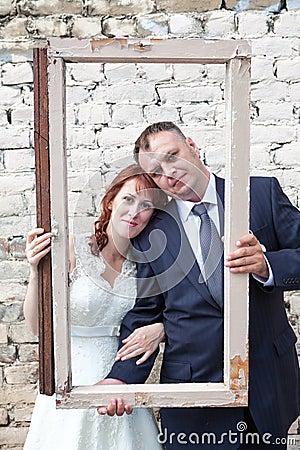 Vertical image of bride and groom looking through portrait frame Stock Photo