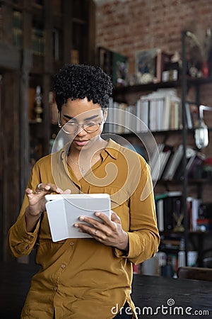 Vertical image concentrated young African American woman using tablet. Stock Photo