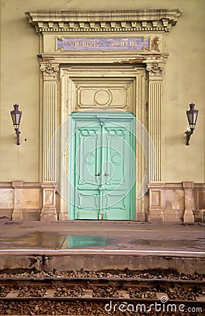 Vertical image of a green door of a church with wall lamp on either side Stock Photo