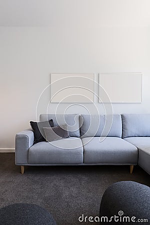 Vertical image of pastel blue sofa with blank artwork above Stock Photo