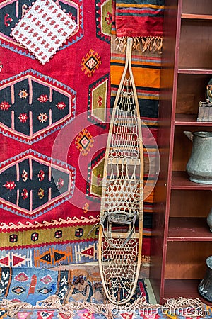 Vertical image of a traditional snowshoe leaning on a wall draped with colorful cloth Stock Photo