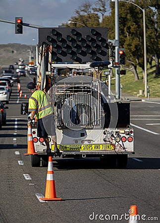 Vertical image of Worker behind utility truck placing bright orange traffic cones on roadway Editorial Stock Photo