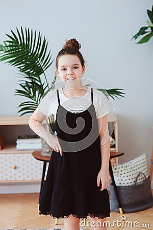 Vertical indoor portrait of happy preteen girl posing in modern scandinavian interior Stock Photo