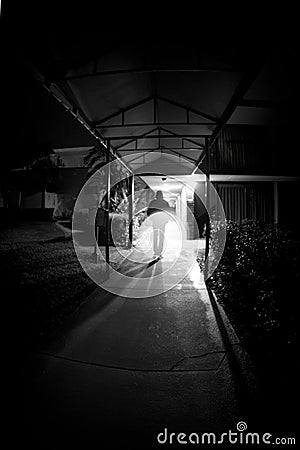 Vertical Monochrome Silhouette of Man Walking Toward Radiant Glow Stock Photo