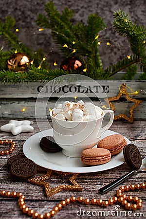 Vertical New Year composition. Coffee with mashmelou in a white cup, macarons, brown beads, stars on the background of glowing Stock Photo
