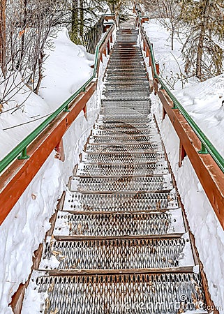 Vertical Outdoor stairway with grated metal treads in a snowy mountain town in winter Stock Photo