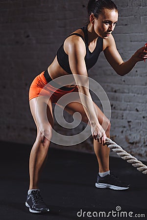 Athletic woman doing some cross fit exercises with battle rope indoor Stock Photo