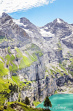 Vertical photo of beautiful Oeschinensee lake by Kandersteg, Switzerland. Turquoise lake surrounded by steep mountains and rocks. Stock Photo