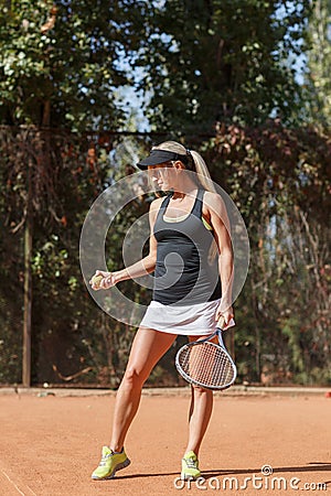 Vertical photo of blonde lady tennis player with ball in hand on court outdoor. Stock Photo