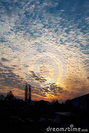 Vertical photo of the dawn over city. The sun rises through the clouds with a fiery disk Stock Photo