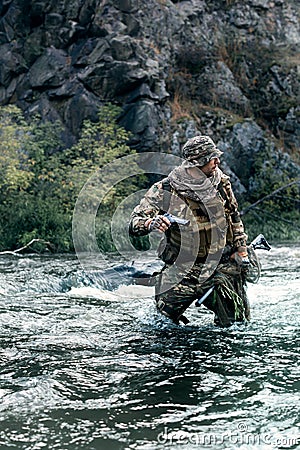 Vertical photo of a mercenary soldier crossing the river after the completion of the sabotage operation. Saboteur Stock Photo