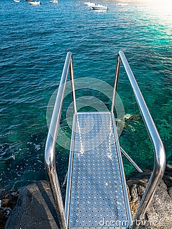 Vertical shot of metal stairs with handrails on the pier at ocean beach Stock Photo