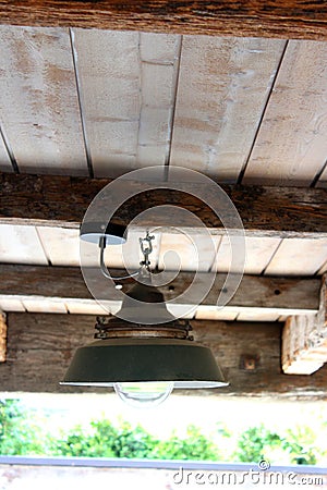 Vertical photo of a metallic lamp hanging from a wooden ceiling Stock Photo