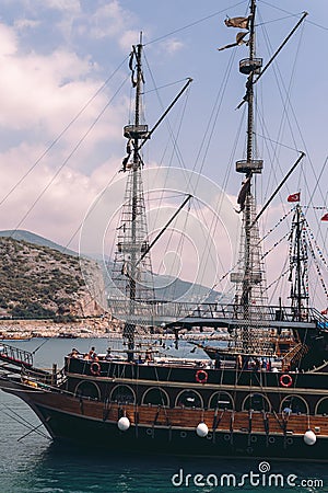 Vertical photo. Old pirate ship on the water of Mediteranean sea. Tourist entertainment, coastal tour. Summer sunny day. Mountain Editorial Stock Photo