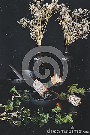 Vertical photo of sage sticks on wiccan witch altar. Two smudge sticks in cast iron holder Stock Photo