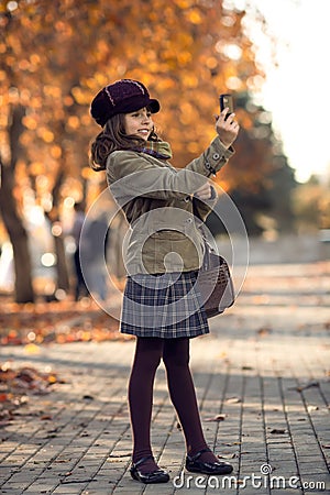 Vertical photo, stylish beautiful little girl photographing on m Stock Photo