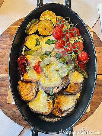 Vertical picture of an assortment of baked vegetables with provolone cheese melted on top. Stock Photo