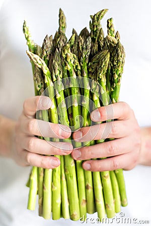 Vertical picture of bundle of green asparagus in hands of man. Mens hands pick bunch of fresh asparagus. Healthy food, vegan, Stock Photo