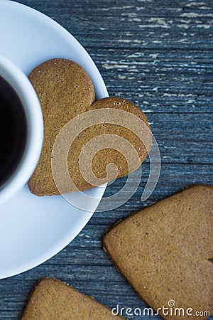 Vertical picture of gingerbread heart shaped biscuit on white porcelain plate. Coffee break with love. Side of coffee Stock Photo