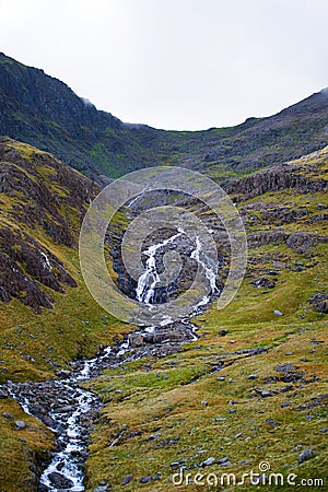 Vertical picture of a small brook through the green hillside of a mountain in Snowdonia, Wales Stock Photo