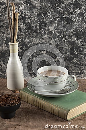 vertical portrait of a cup of coffee on a table with a book and coffee beans Stock Photo