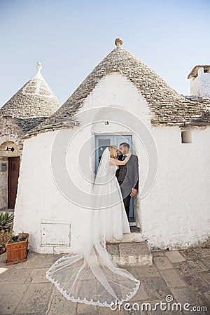 Vertical portrait glad loving romantic married couple, blond woman in white dress and black-haired man in tuxedo, Italy Stock Photo