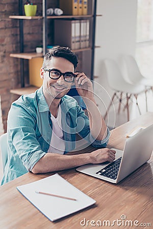 Vertical portrait of young businessman in jeans shirt and glasses using computer for his work Stock Photo