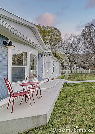 Vertical Puffy clouds at sunset Front yard of a house with concrete deck and white wooden fence Stock Photo