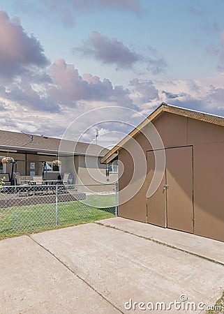 Vertical Puffy clouds at sunset Small wooden shed exterior with a concrete pad flooring Stock Photo