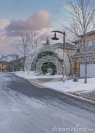 Vertical Puffy clouds at sunset Townhouses exterior with attached garage and a driveway cleared Stock Photo