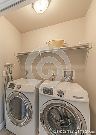 Vertical Reached in laundry with white bi-fold doors and laundry units below the shelf Stock Photo