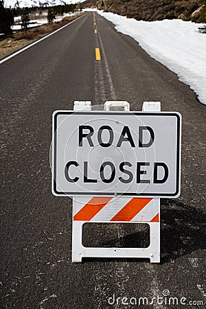 Seasonal Road Closed Sign on Pavement with Snow - Vertival Stock Photo