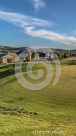Vertical Scenic golf course landscape against houses and mountain under sky and clouds Stock Photo