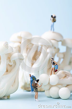Vertical selective focus closeup of a toy people hiking on the mushrooms on a blue background Stock Photo